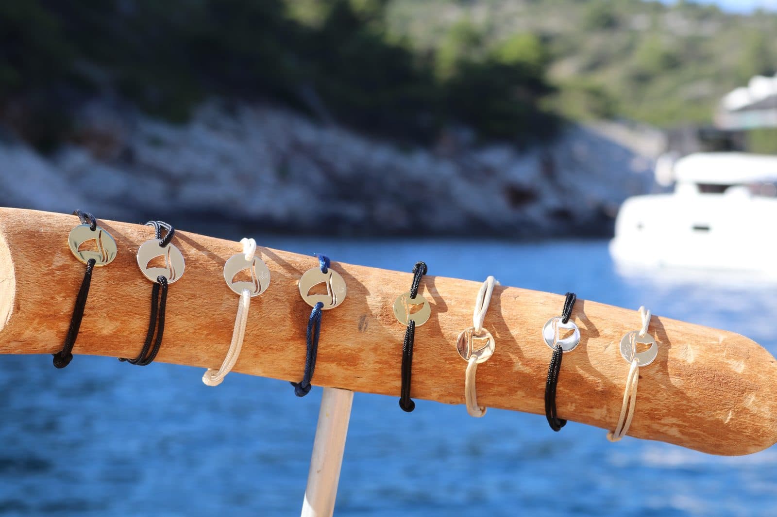 Gaab Save the Sharks bracelets on a driftwood display stand overlooking the sea
