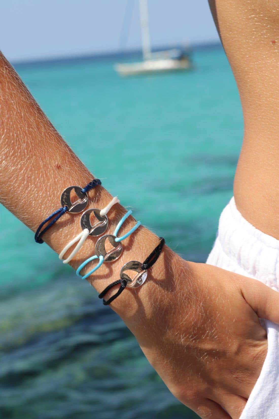 Stacked Gaab shark bracelets in navy, white, blue and black cords